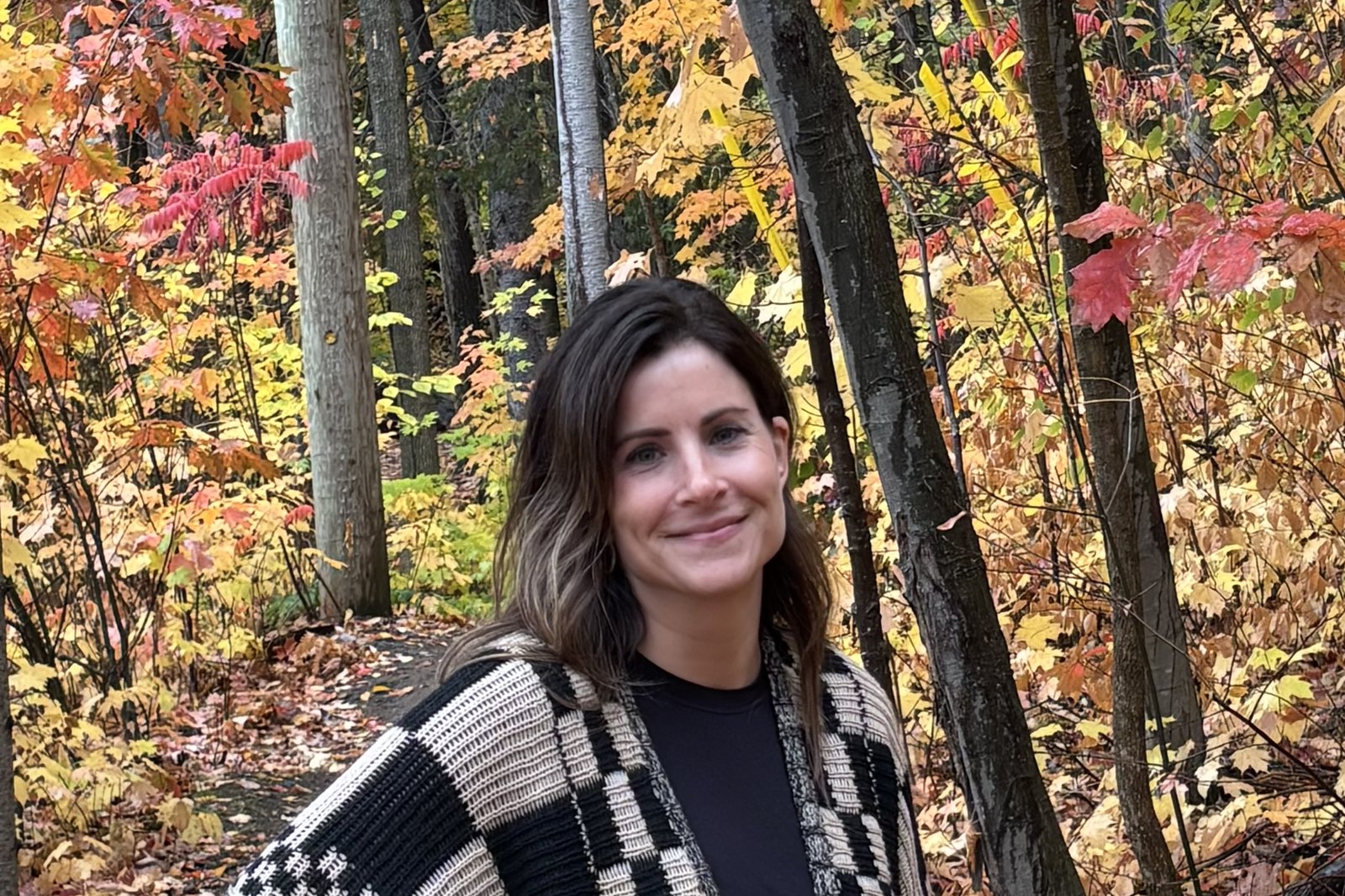 Melissa Abraham, owner of All Things Lovely Cheesecakes, on a wooded trail among fall leaves in North Bay