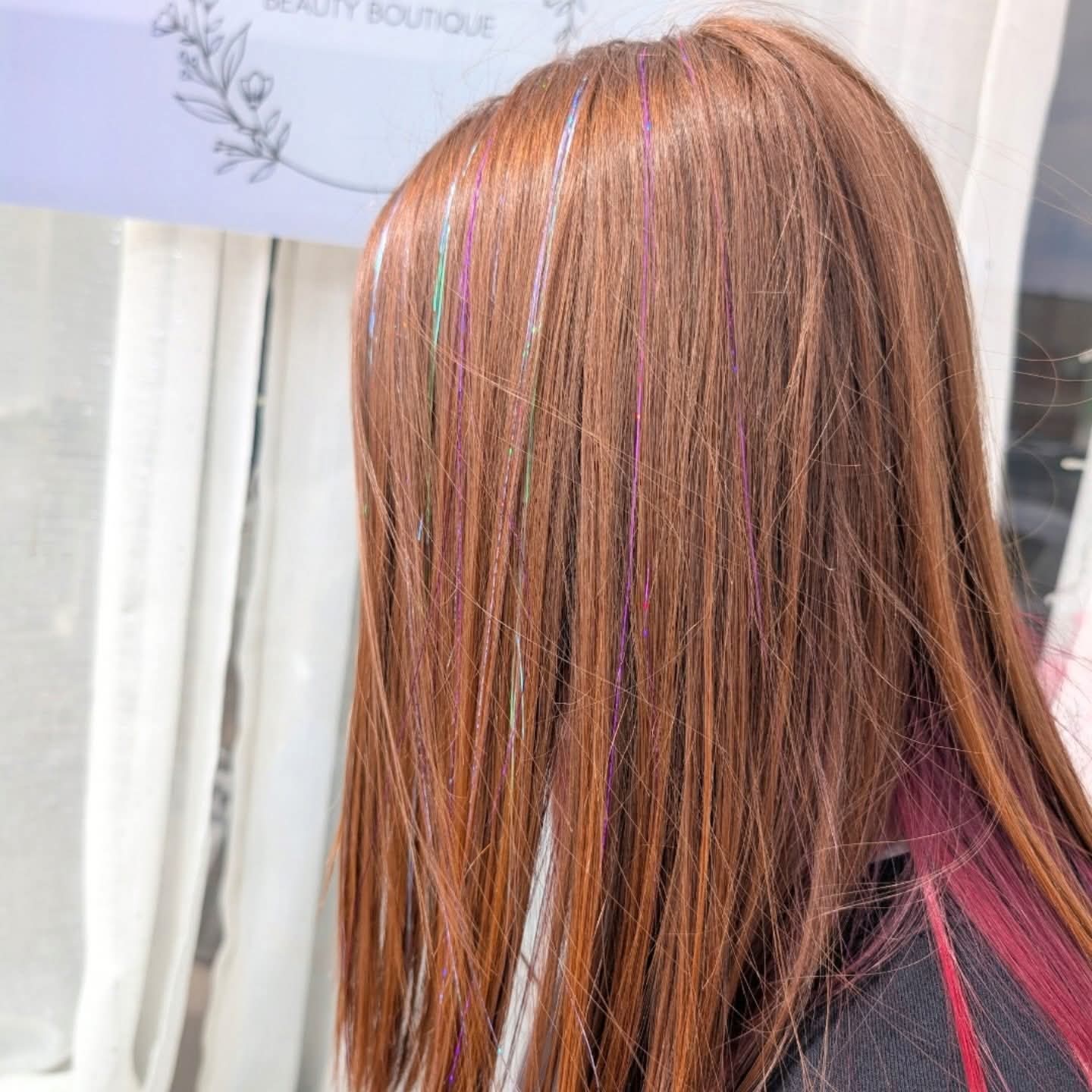 Coloured glitter hair tinsel strands woven through long auburn hair at Brea's Beauty Boutique