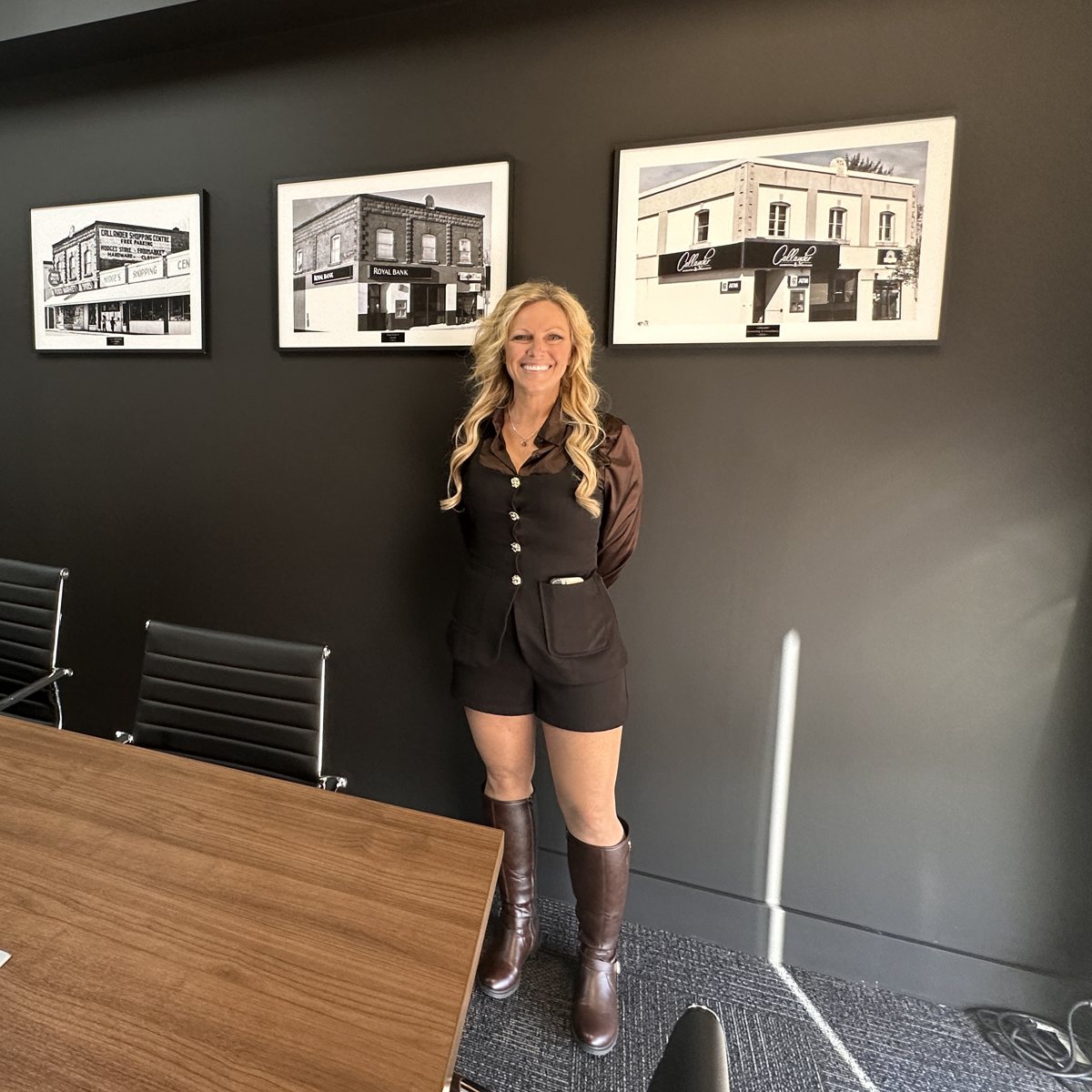 Kim McVeety in front of framed photos of her building, from the Royal Bank years to the Callander Accounting sign