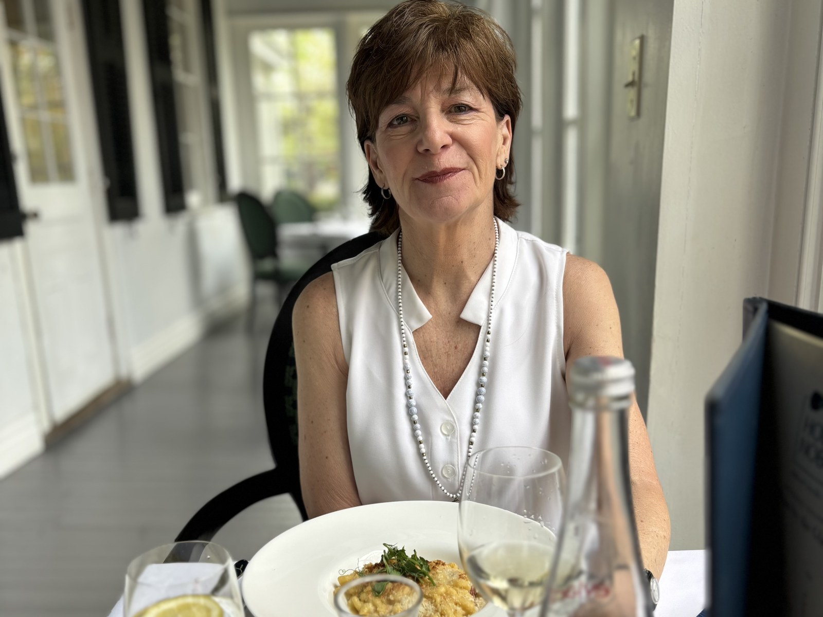 Linda Nardilli Morrin seated at a set table with a plate of pasta