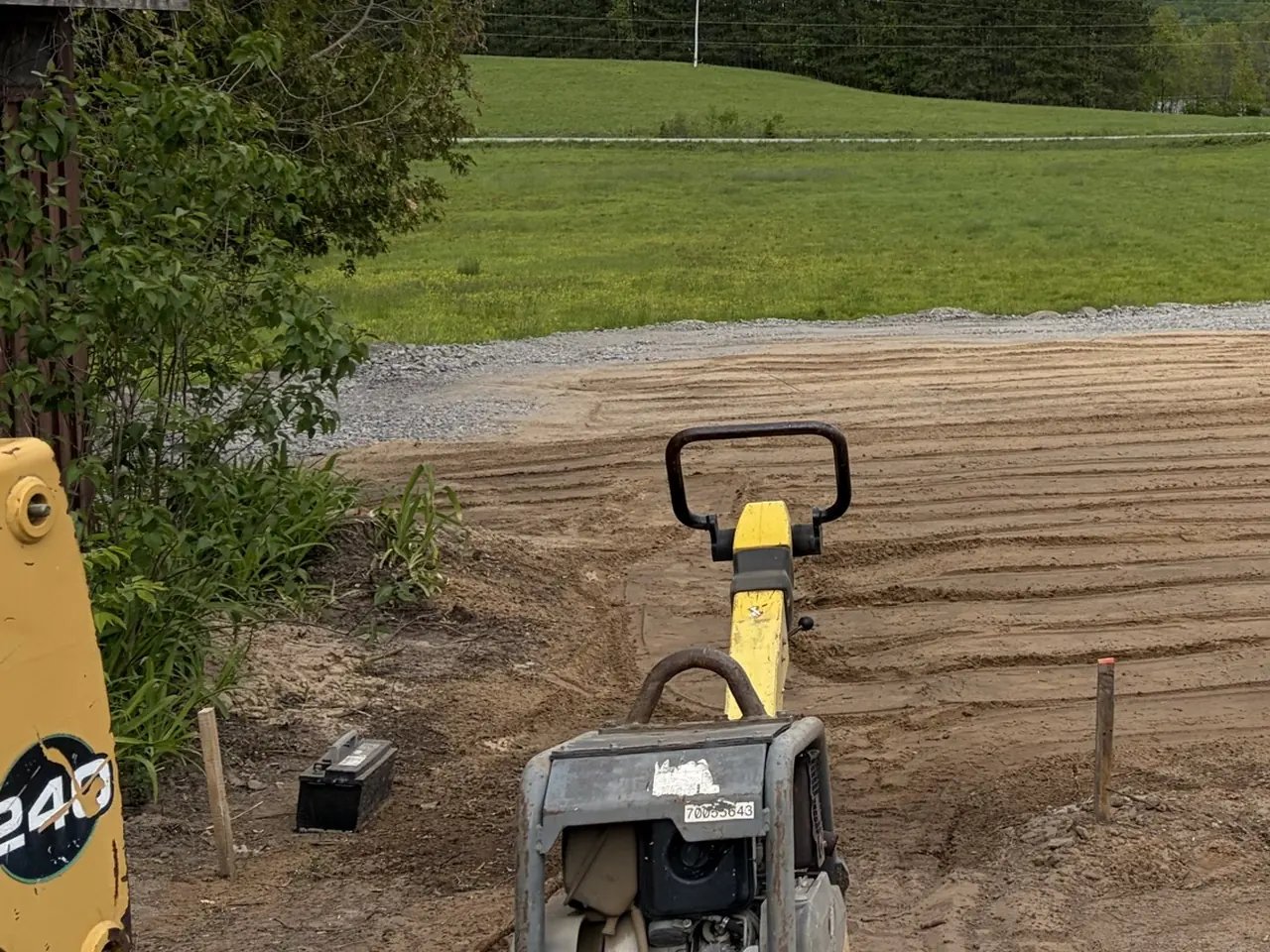 Plate compactor compacting a graded base on an Edwards Landscape and Construction job site