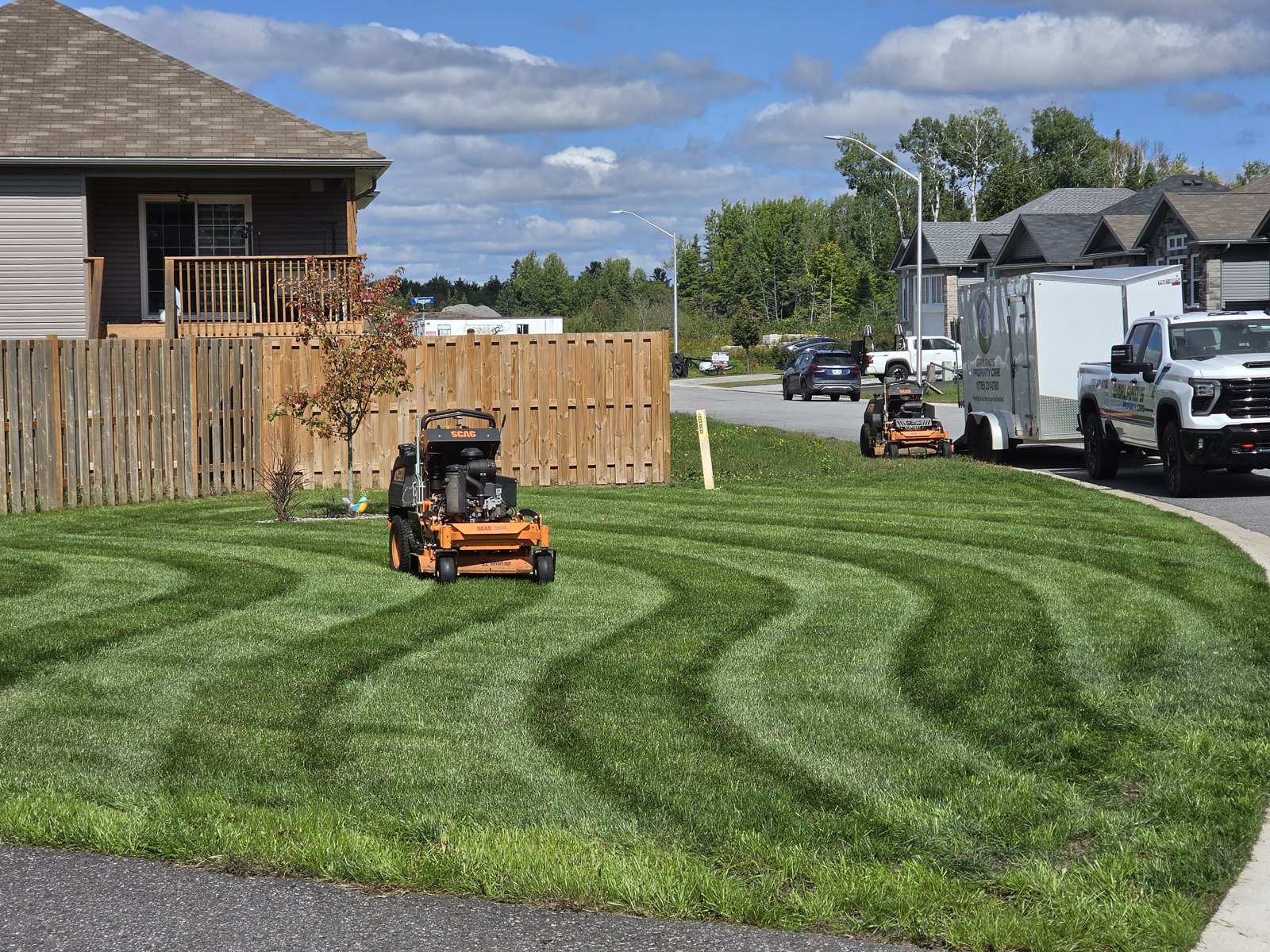Wave striped lawn with SCAG stand on mowers and the Garland's Property Care truck and trailer in North Bay
