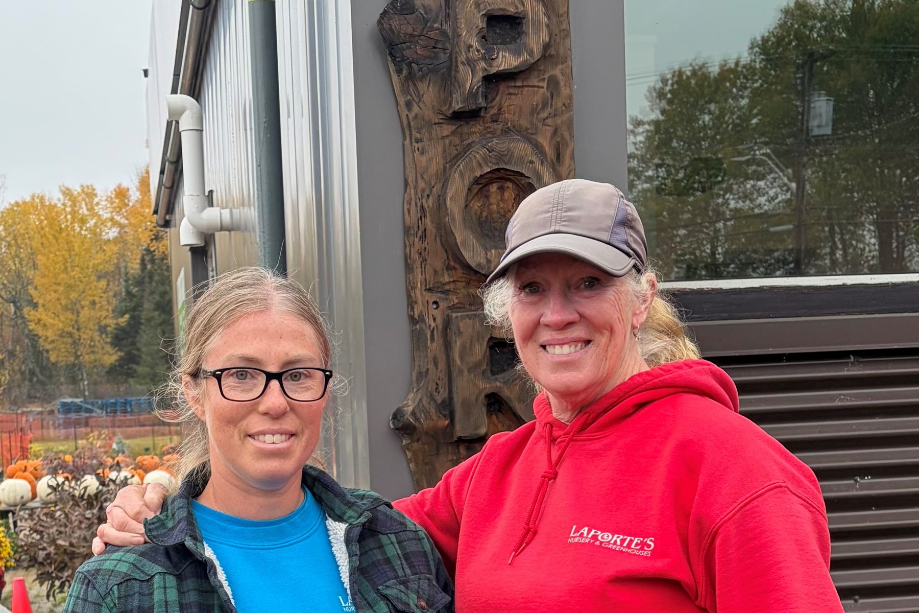Kelsey McMullen and her mom Lori Laporte outside Laporte's Nursery in North Bay, beside the carved Laporte's sign