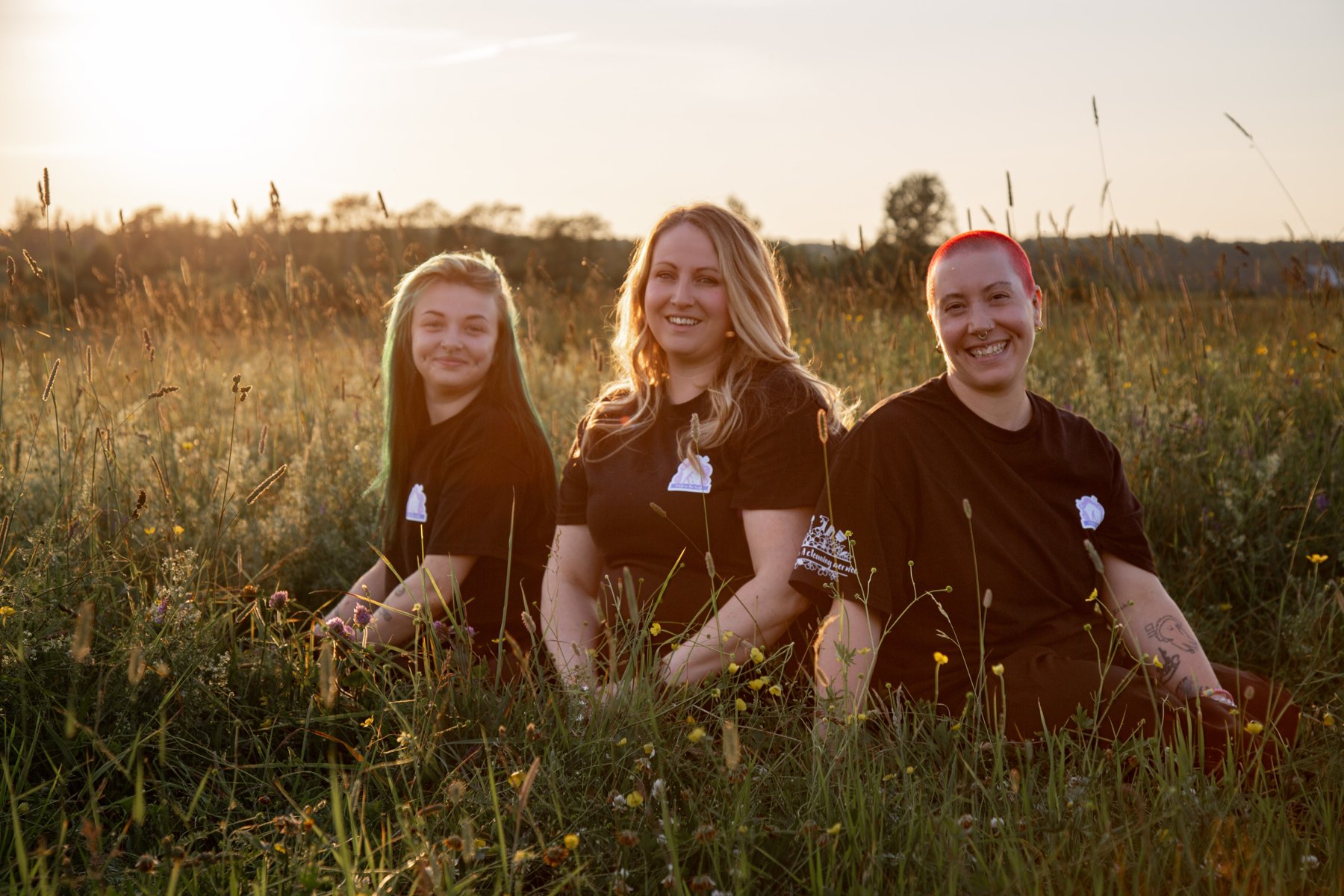 The Maid In The North team in a field of summer grass at sunset