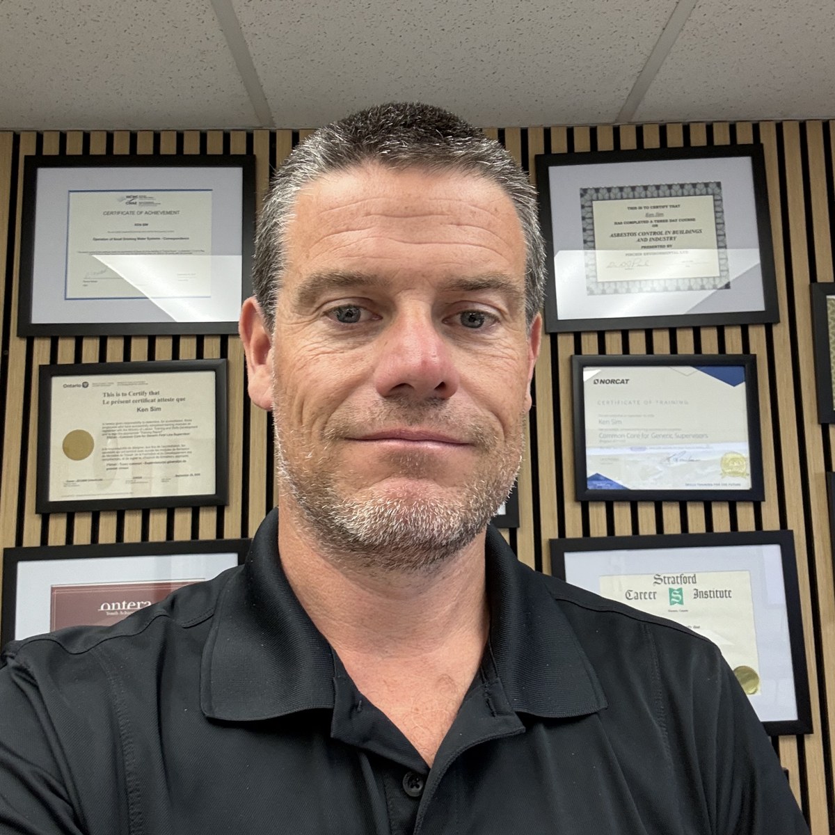 Ken Sim in his North Bay office in front of his framed training certificates
