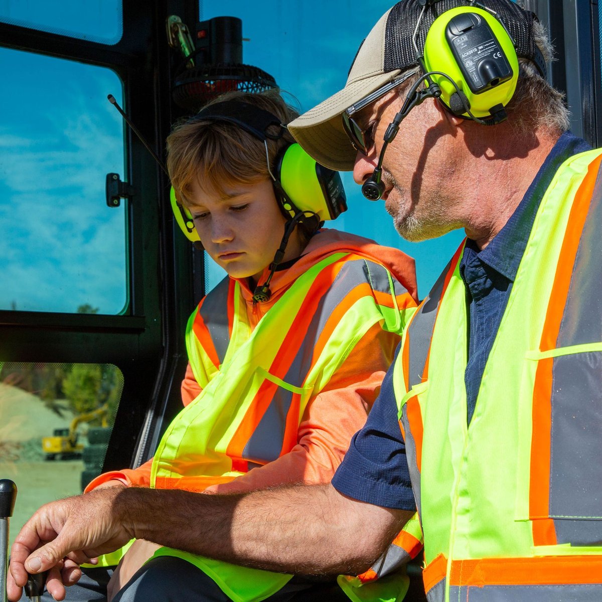 A MASHinery machine coach in a headset guiding a young operator at the controls